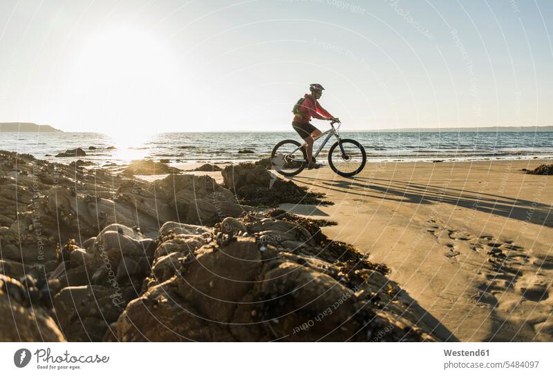 Frankreich, Halbinsel Crozon, Mann mit dem Fahrrad am Strand fahren Außenaufnahme draußen im Freien Reisende Reisender unterwegs auf Achse in Bewegung