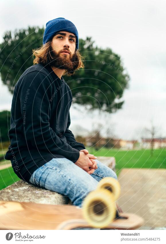 Porträt eines bärtigen jungen Skateboardfahrers Europäer Kaukasier Europäisch kaukasisch sitzen sitzend sitzt Freizeit Muße Fokus Auf Den Vordergrund