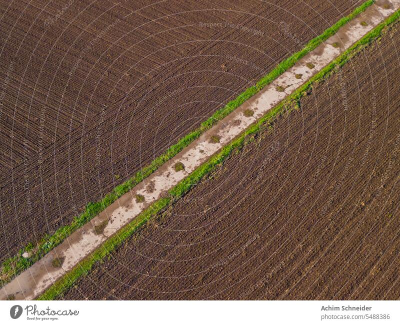 Feldweg diagonal zwischen Äckern mit fruchtbarem Land nach dem Regen Acker Ackerboden Aerial Shot Anbau Betonweg Boden Drohnenbild Drohnenperspektive Dürre
