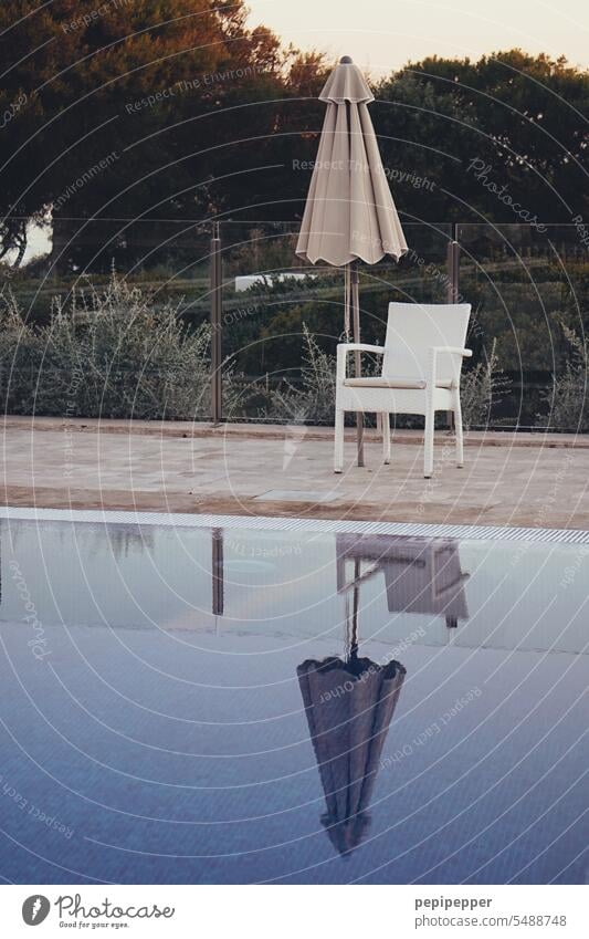 Abendstimmung – zusammengeklappter Sonnenschirm hinter einem Stuhl am Pool Schwimmbad Wasser Sommer blau nass Schwimmen & Baden Erholung schwimmen Erfrischung