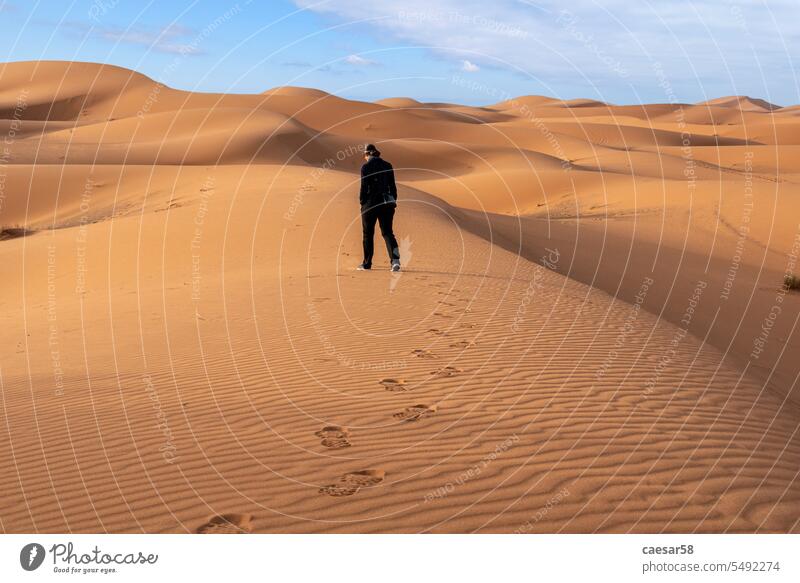 Eine Person wandert durch die Wüste Erg Chebbi in der afrikanischen Sahara wüst Wanderung allein Symbol Einsamkeit Landschaft Himmel blau Dunes Düne Fußstapfen