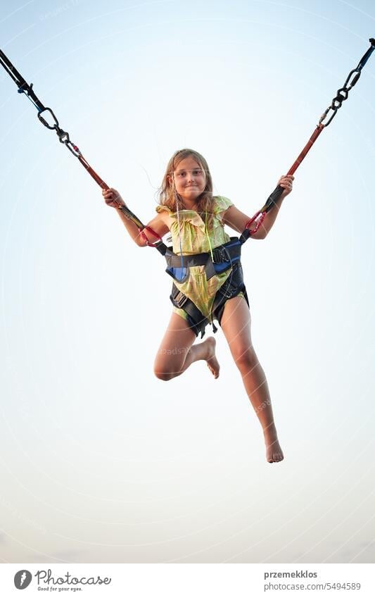 Bungee-Springen auf dem Trampolin. Kleines Mädchen hüpft auf Bungee-Springen im Vergnügungspark in den Sommerferien. Super Mädchen springend Vergnügen Park