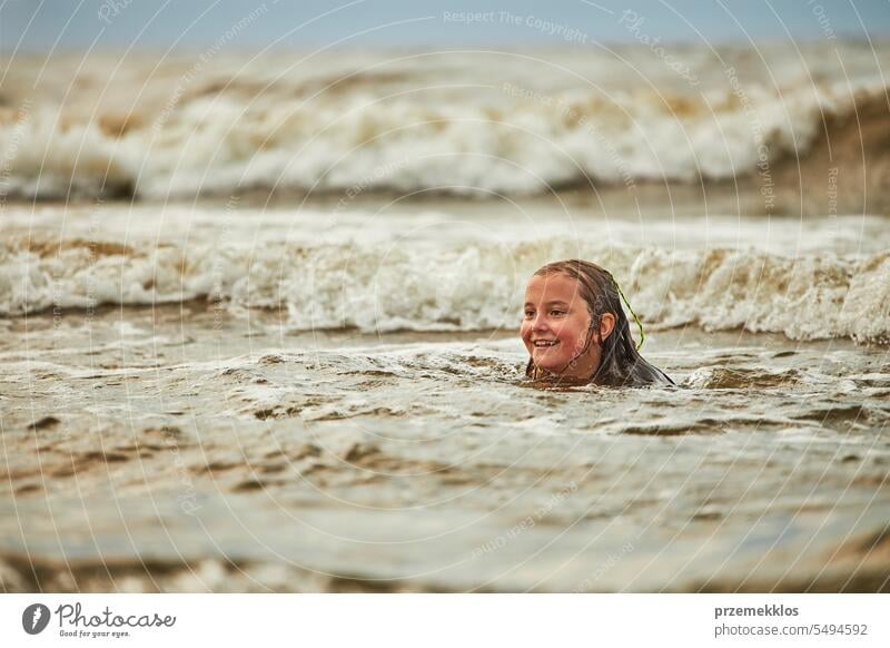 Kleines Mädchen spielt mit Wellen im Meer. Kind plantscht spielerisch in Wellen. Kind springt ins Meer. Urlaub am Strand. Wasser plätschert Sommer Ferien MEER
