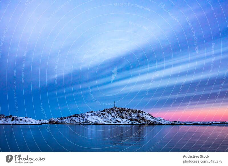 Snowy Berge in der Nähe von Meer gegen bewölkten Himmel bei Sonnenuntergang Meereslandschaft Berge u. Gebirge MEER felsig Kamm Wasser Formation Abend Winter