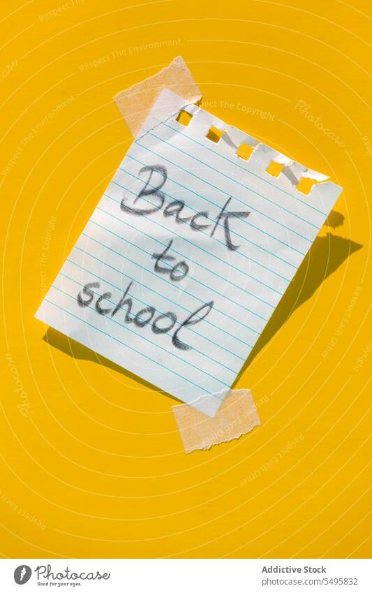 Zettel mit der Nachricht "Zurück in die Schule" an eine gelbe Wand geklebt zurück zur Schule Schreibwarenhandlung Erinnerung schreiben Notebook Page Linie