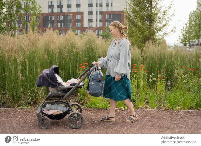 Frau schiebt Baby im Kinderwagen beim Spaziergang im Park Mutter schieben Pflanze Familie Säugling Buggy Rucksack Lifestyle grün Liebe Zusammensein Pflege