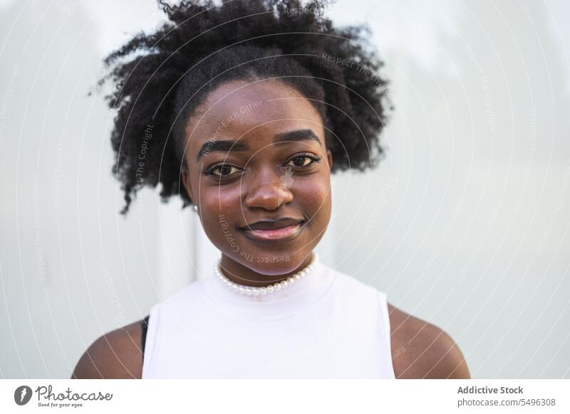 Lächelndes schwarzes Teenager-Mädchen im weißen Kleid positiv Frisur Glück Stil Porträt schlank Behaarung jung Afro-Look Frau Afroamerikaner Dame lässig froh