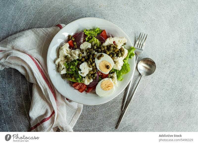 Keto-Salat mit Blattsalat, gekochten Eiern, Kapern, Tomaten, roten Zwiebeln und Blumenkohlgemüse. Teller Speise Keton Salatbeilage grün Gemüse traditionell