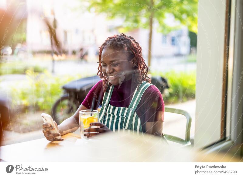 Porträt einer schwarzen nicht-binären Person, die in einem Café im Freien sitzt echte Menschen positiv selbstbewusst Erwachsener junger Erwachsener Lifestyle