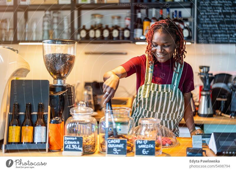 Porträt einer Genderqueer-Barista, die am Tresen eines Cafés Kaffee zubereitet echte Menschen positiv selbstbewusst Erwachsener junger Erwachsener Lifestyle