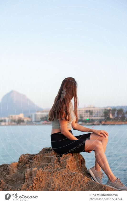 Frau sitzt auf einem Felsen am Strand. Tourist Foto. weibliche Solo-Reise. Mädchen Insel Spanien Berge u. Gebirge felsig Landschaft reisen Küste Urlaub Stein