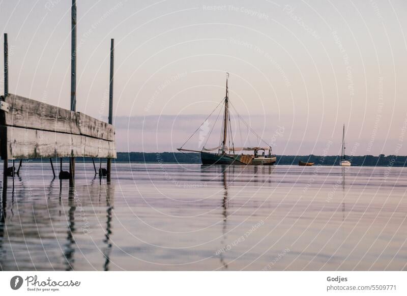 Altes Segelschiff neben einem Steg auf dem Wasser in der Abenddämmerung, Spiegelung im Wasser Segelboot Boot Schiff Himmel Segeln Jacht Meer Urlaub nautisch