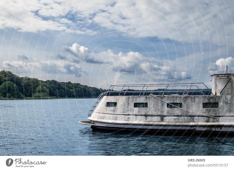 Ein in die Jahre gekommenes weißes Hausboot auf einem großen See bei blauen Himmel mit Wolken Boot Wasser Außenaufnahme Menschenleer Schifffahrt