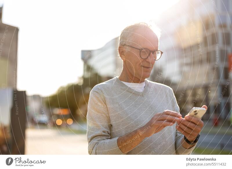 Älterer Mann mit Smartphone in der Stadt Menschen Kaukasier Stehen Gesundheit Stadtleben graues Haar genießen Straße lässig Tag Porträt außerhalb echte Menschen