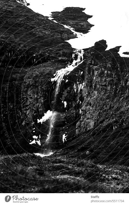 Schnee, Felsen und ein Wasserfall auf Island Ostisland isländische Natur isländische Landschaft Felswand Felsformation felsig eisig karg Wasserfallausschnitt
