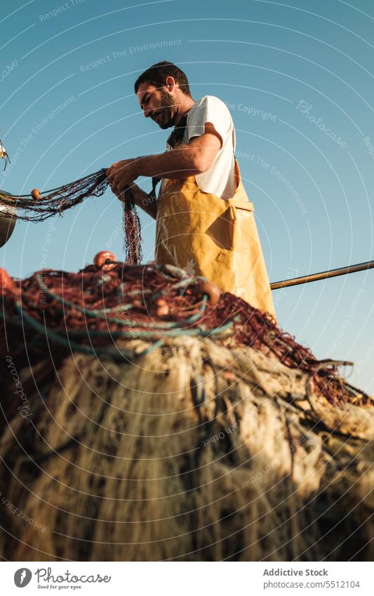 Fischer knüpft Netz auf Segelboot im Meer auf - ein lizenzfreies