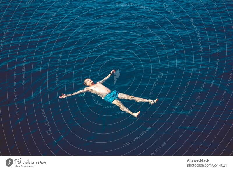 Mann mittleren Alters liegt mit ausgestreckten Armen und Beinen rücklings im blauen Meer Meere Wasser Ozean Schwimmen & Baden baden H2O maritim treiben lassen