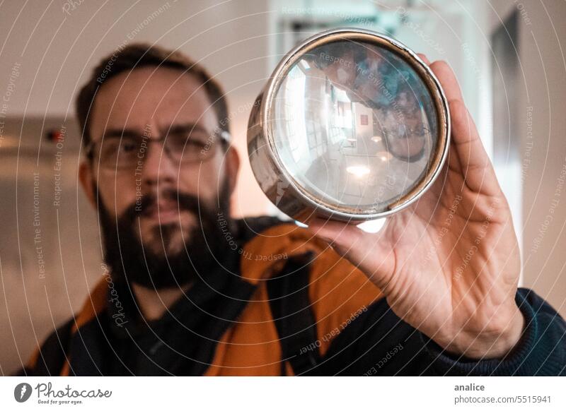 Mann schaut durch ein Vergrößerungsglas Brille Lupe Objektive durchblickend Blick durch Glas Beteiligung beobachtend Vollbart erkunden Entdecker Analysieren