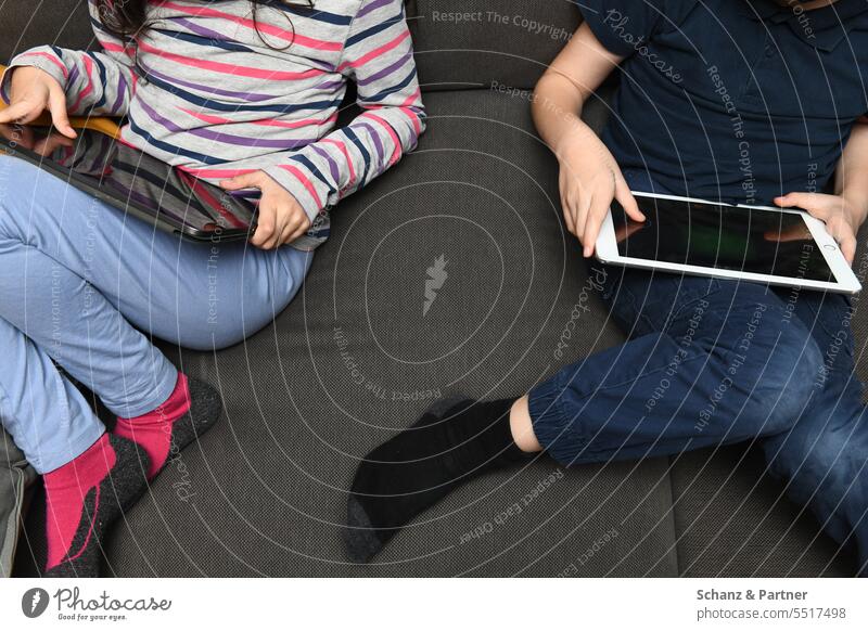 zwei Kinder sitzen nebeneinander auf der Couch und spilen an ihren Tablets Gaming ipad zocken Technik & Technologie Spielen Internet Computer online digital