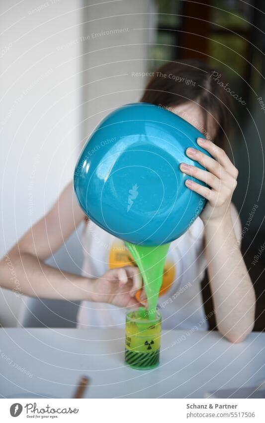 Kind schüttet grünen Schleim aus einer blauen Schüssel un einen Becher mit radioaktiv Warnhinweis spielen Schleimi glibberig eklig Spielzeug