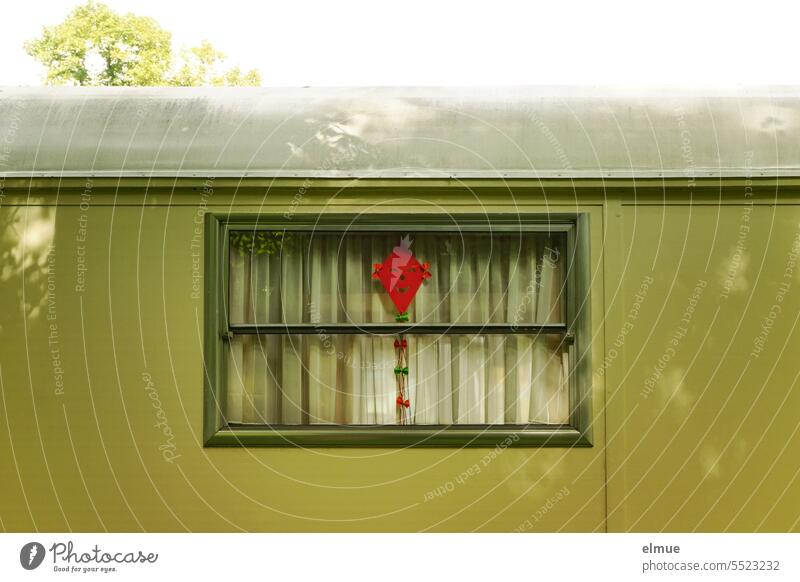gebastelter roter Papierdrachen hinter dem Fenster eines grünen Wohnwagens / Herbst Drachen Flugdrachen Drachenfliegen Drachensteigenlassen Freizeit & Hobby