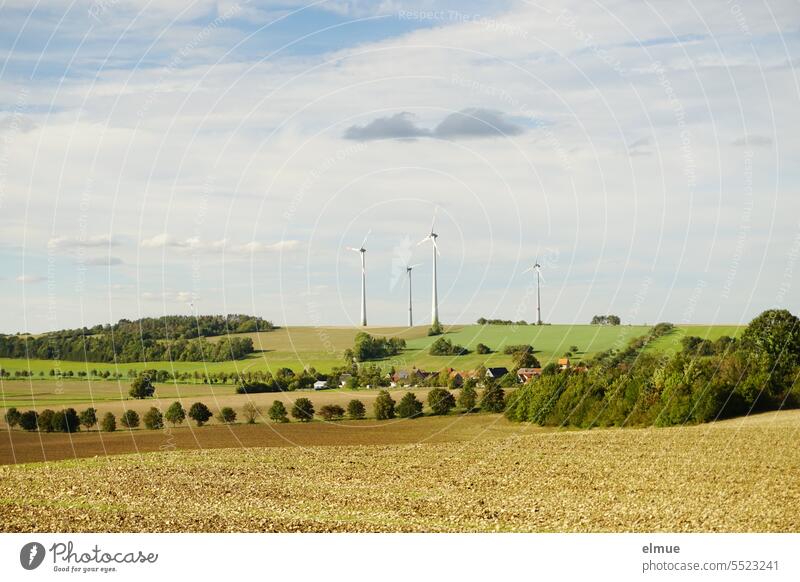 Windräder in hügeliger Landschaft mit Bäumen und abgeernteten Feldern / Frühherbst Windenergie Erneuerbare Energie Hügelland Feldwirtschaft nachhaltig