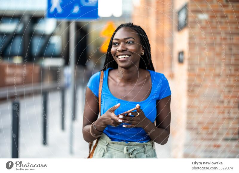 Porträt einer jungen Frau beim Telefonieren in der Stadt Erwachsener attraktiv schön schwarz Selbstvertrauen selbstbewusst cool Mädchen Frisur Freizeit