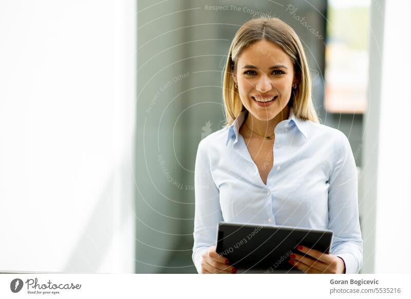Junge Frau mit digitalem Tablet im modernen Büroflur stehend Erwachsener attraktiv schön Business Geschäftsfrau lässig heiter Mitteilung Unternehmen