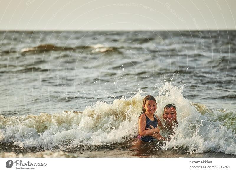 Kleines Mädchen und ihr Vater spielen mit Wellen im Meer. Sommerurlaub mit der Familie. Kind plantscht spielerisch mit Wellen. Sommerurlaub am Strand Ferien