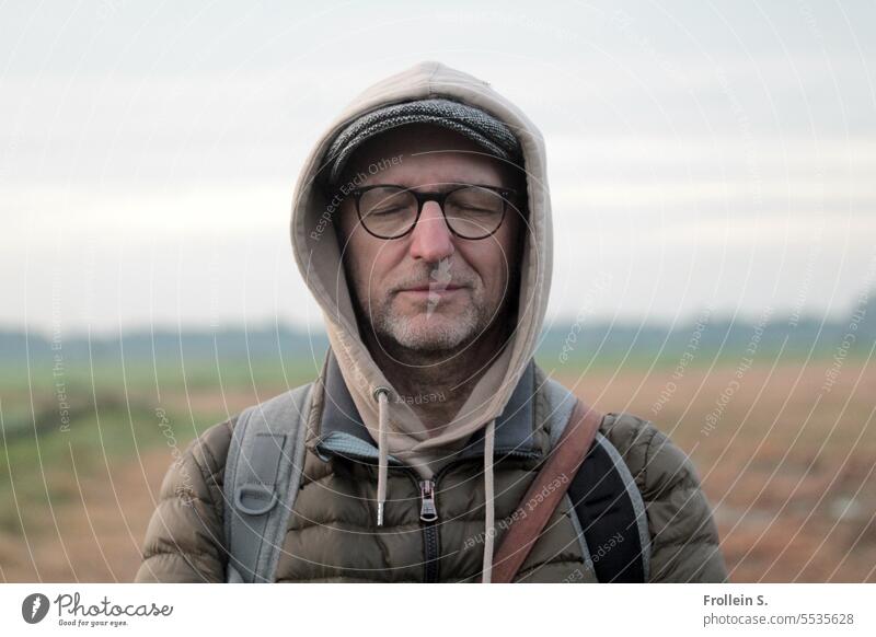 Weites Land | traumhaft Portrait geschlossene Augen männlich Kapuze kalt Landschaft Jacke Ruclsack Horizont
