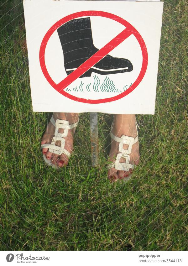 Betreten verboten – junge Frau steht mit beiden Füßen auf einem Rasen, trotz eines Verbotsschildes betreten verboten Schilder & Markierungen Verbote