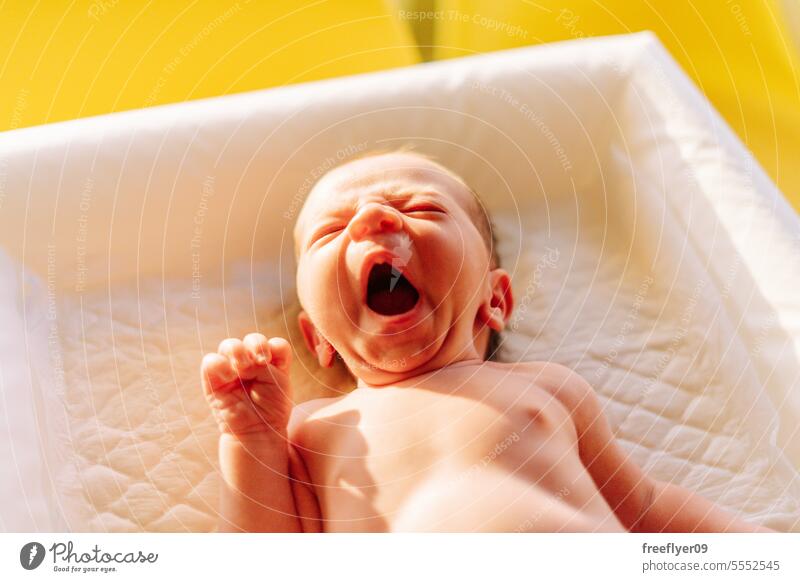 Porträt eines Neugeborenen, das auf einer Wickelkommode gähnt Baby neugeboren gähnend schläfrig schlafen Textfreiraum Elternschaft Mutterschaft Unschuld Leben