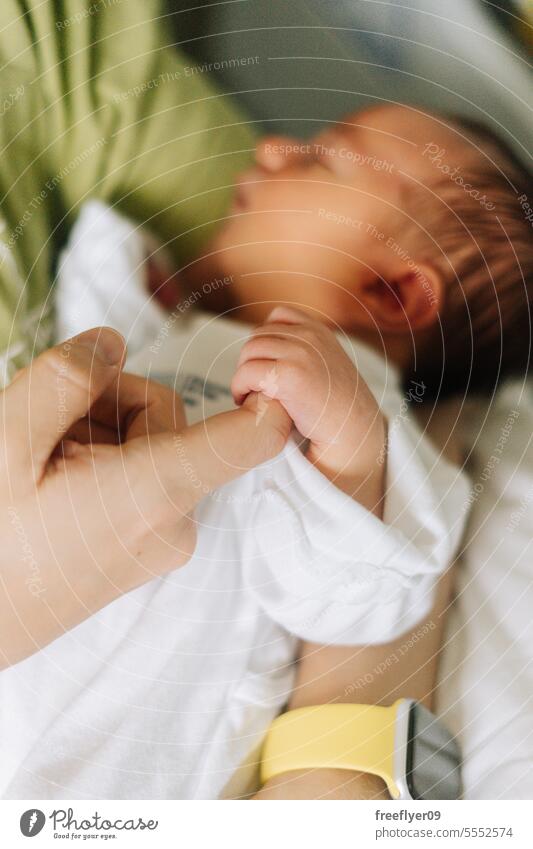 Detail einer neugeborenen Hand, die den Finger des Vaters hält Baby Beteiligung Porträt Pflege aufpassend Textfreiraum Erstgeborenes Vaterschaft Elternschaft