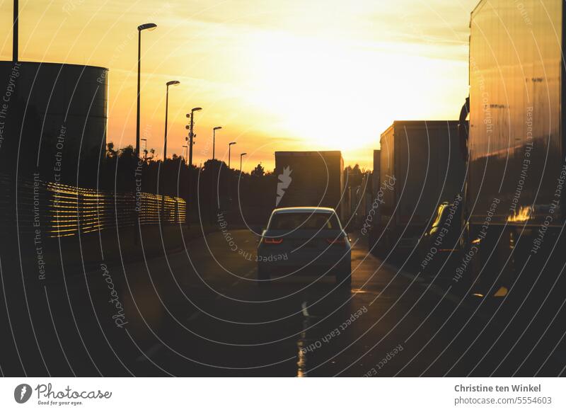 Fahrt in den Sonnenuntergang Straße Autos urban Fahrzeuge Straßenlaternen LKW Sonnenuntergangsstimmung Gegenlicht Gegenlichtaufnahme Verkehr PKW Licht