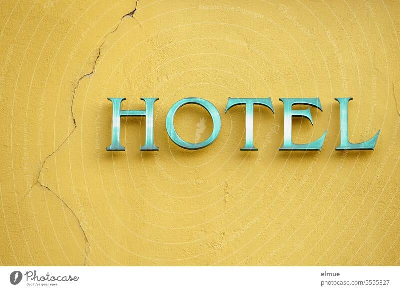 HOTEL steht in grünen Buchstaben an einer gelben, mit Rissen durchzogenen Hauswand Hotel Übernachtung Unterkunft Quartier übernachten Ferien & Urlaub & Reisen
