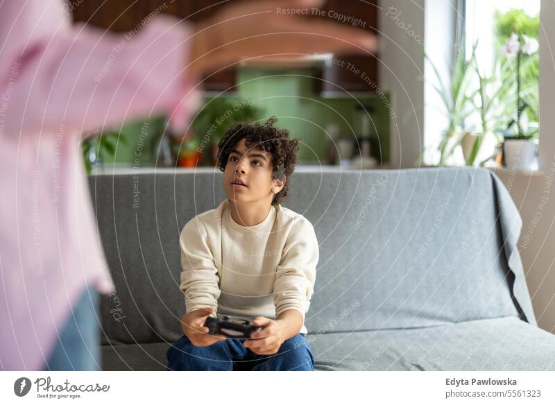 Teenager spielt Videospiele, während seine Mutter nicht glücklich darüber ist echte Menschen Erwachsener Appartement Bonden Junge Kind Familie Frau heimwärts