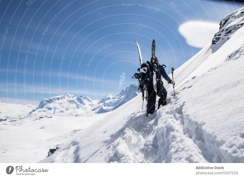 Unbekannte Person, die einen schneebedeckten Berg besteigt Skifahrer Schnee Klettern Berge u. Gebirge unkenntlich Herausforderung Mast deckend Rückansicht