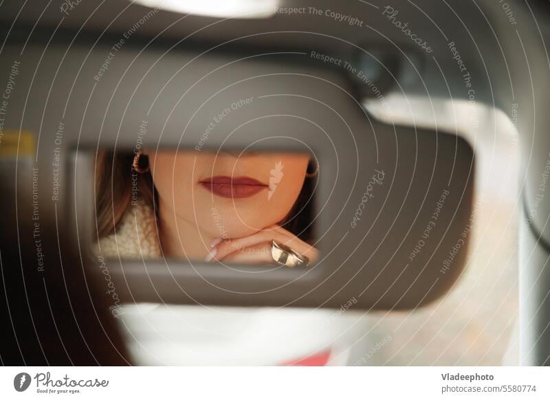 Frau mit Lippen im Schminkspiegel, während sie im Auto sitzt. Spiegel PKW schön Make-up attraktiv Fahrer Schönheit jung Automobil Lippenstift Fahrzeug Kaukasier