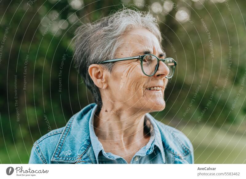 Ältere lächelnde Frau, die nach ihrer Pensionierung einen Ausflug macht und sich ausruht, während sie die herrlichen Sehenswürdigkeiten betrachtet mental