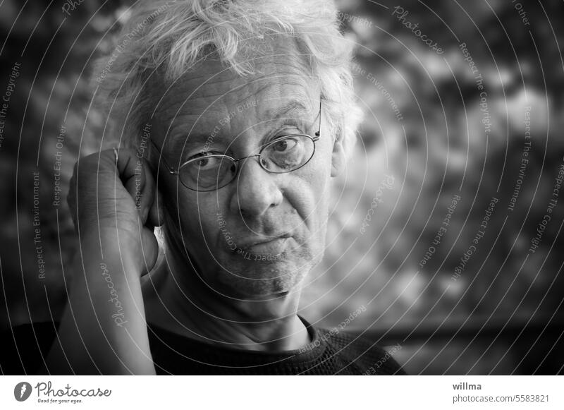 Mann mit Brille, nachdenklich zuhörend und mit skeptischem Blick Porträt zweifelnd beobachten weißhaarig sw grauhaarig authentisch