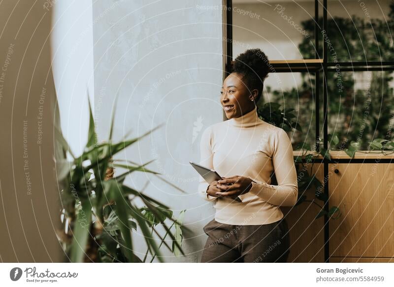 Junge afroamerikanische Frau steht mit digitalem Tablet im Büro Afrikanisch afrikanische ethnische Zugehörigkeit Amerikaner schwarz Business Geschäftsleute