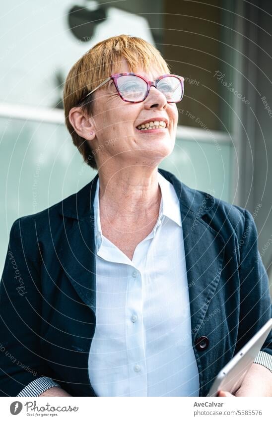 Ältere Geschäftsfrau vor einem Firmengebäude, glücklich in die Kamera lächelnd, Frau im Geschäft Büro Kollege Business Person Frauen Porträt Lifestyle Glück