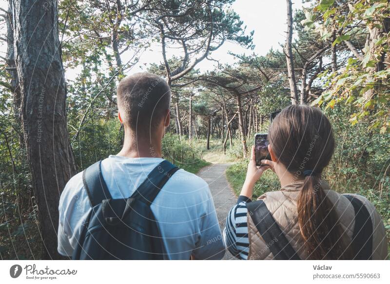 Ein reisendes Paar hält seine Entdeckungen mit dem Handy fest. Ein Park bei Blankenberge. Wilde Natur.  Gemeinsam etwas erleben Datierung Telefon romantisch