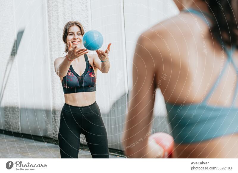 Zwei fitte Frauen treiben zusammen Sport und benutzen einen Medizinball, um ihren Körper zu straffen. Urbane Szene. Fitness passen im Freien urban Freunde