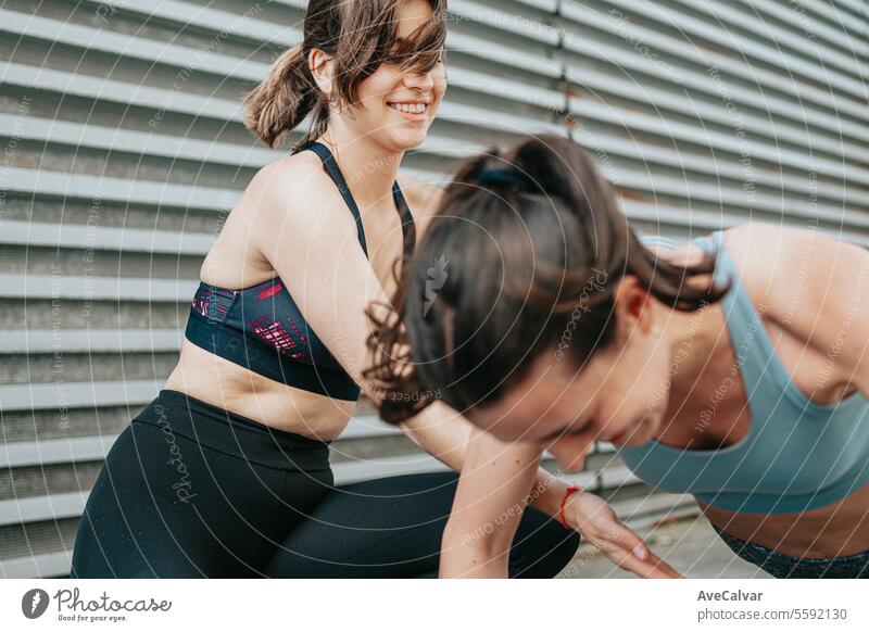 Eine Trainerin bringt einer Schülerin bei, wie man Liegestütze richtig macht - Sport im Freien in städtischer Umgebung Lifestyle Fitness trainiert. Person