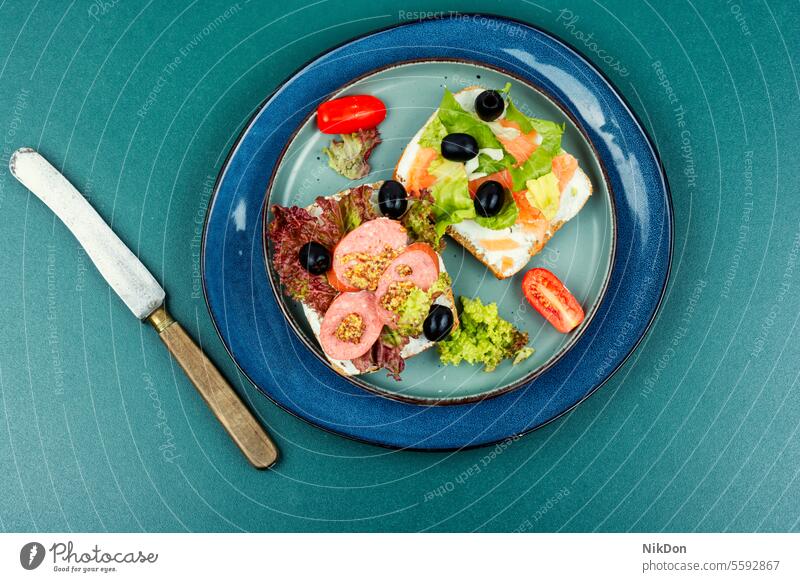 Frische Sandwiches mit Fisch und Würstchen. Belegtes Brot Wurstwaren Lebensmittel grün Salat Lachs Snack Mittagessen Frühstück Zuprosten lecker Scheibe