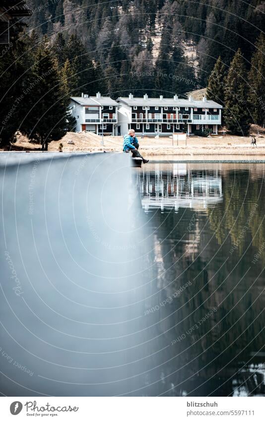 Ein Junge sitzt auf einem Steg am See November Kindheit Familie & Verwandtschaft Freundschaft Fröhlichkeit Bergsee Winter Herbst Lenzerheide Schweiz Berge