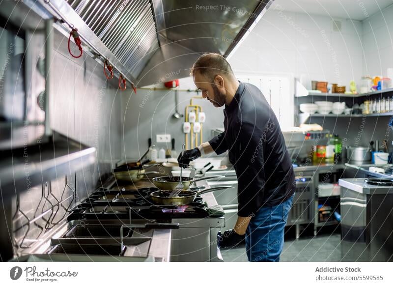 Männlicher Koch kocht in der Küche auf einer Bratpfanne Mann Küchenchef braten Restaurant Lebensmittel professionell Arbeit Pfanne kulinarisch Gas vorbereiten
