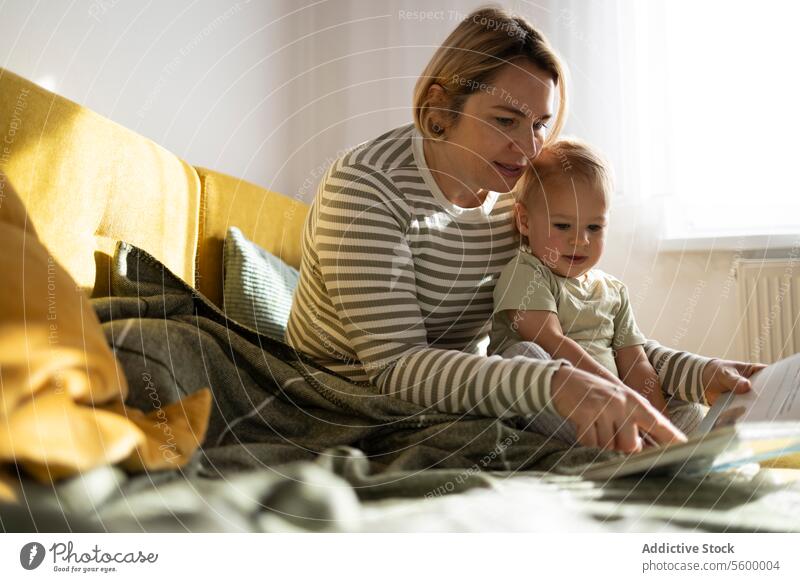 Mutter und Kleinkind genießen ein Buch zu Hause lesen heimwärts Liege sonnig warm Dekor Bildung Bonden Familie Lernen Zusammengehörigkeitsgefühl im Innenbereich