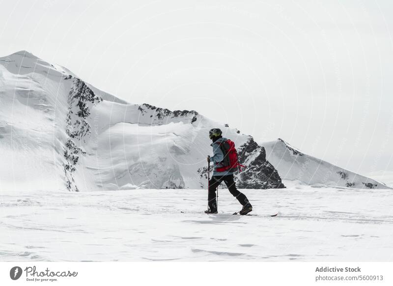 Ganzer Körper eines anonymen Mannes beim Skifahren in einer verschneiten Landschaft an einem sonnigen Tag im Winter in den Schweizer Alpen Skifahrer Schnee Mast